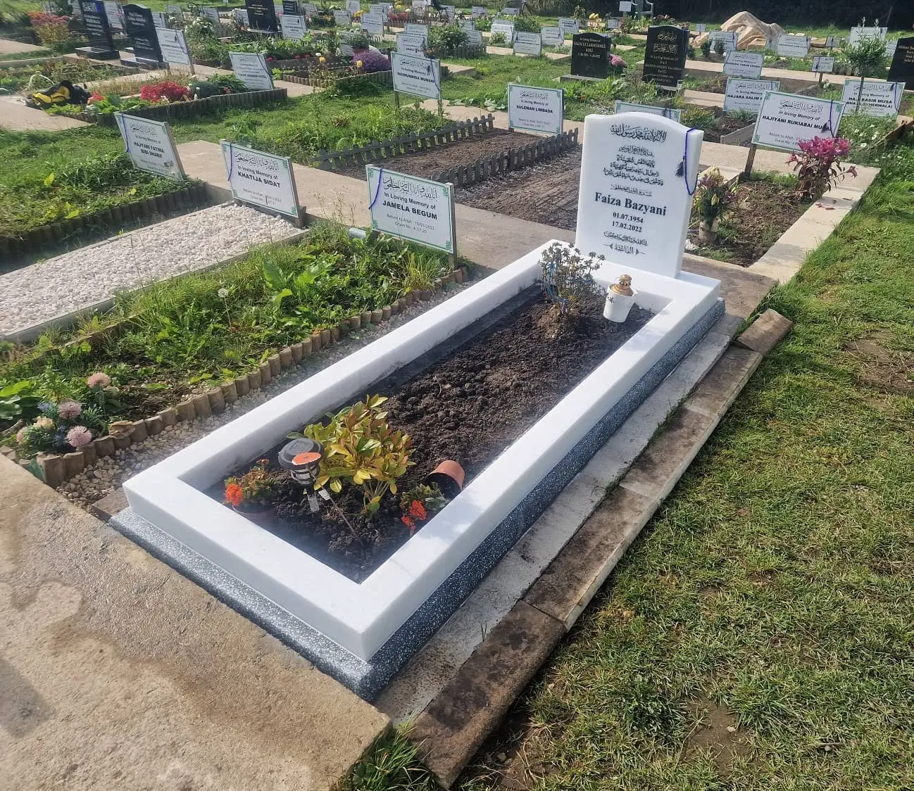 White headstone with Arabic inscription and a matching full kerb surround