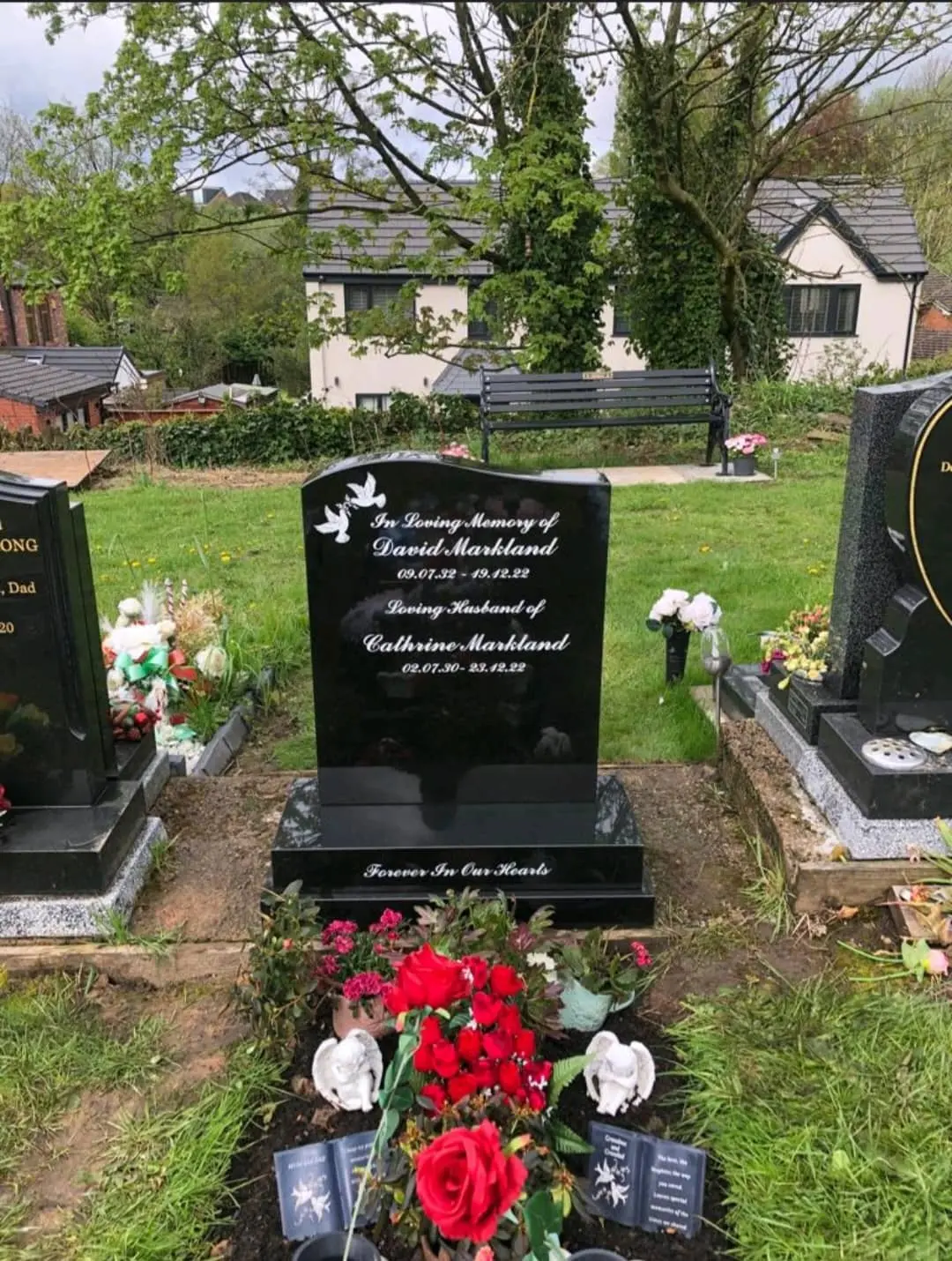 Black headstone with a softly curved top, white script lettering and two dove motifs