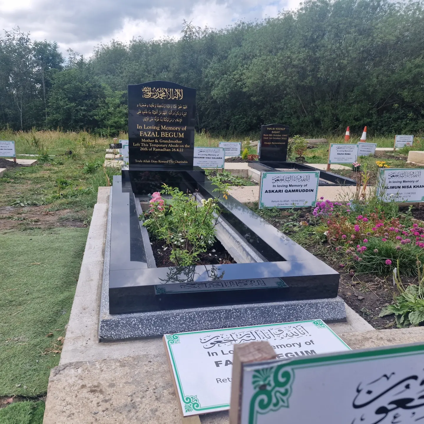 Polished black memorial with a shallow curved headstone, gold inscription and straight full kerb surround